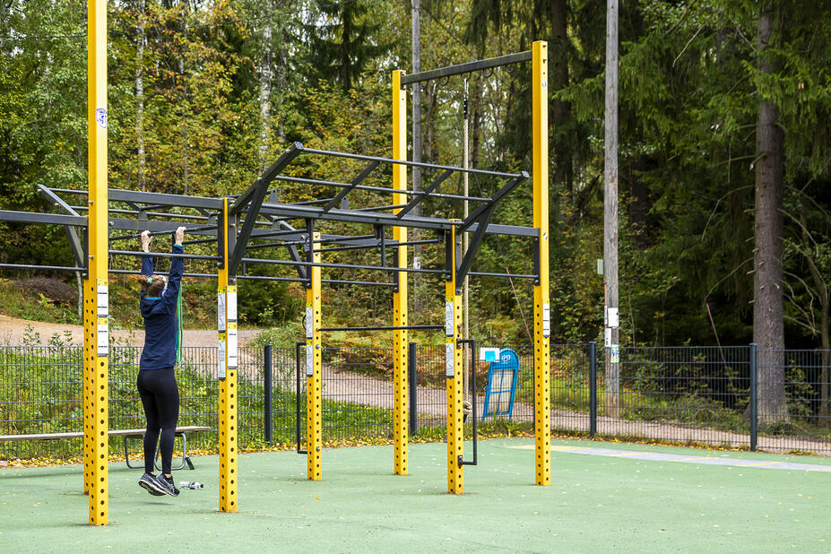 Henkilö Pirkkolan ulkokuntosalin monitoimilaitteessa.