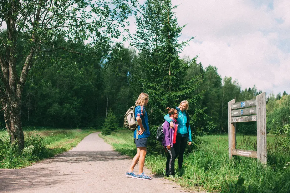 Kolme henkilöä katsomassa opastetaulua.
