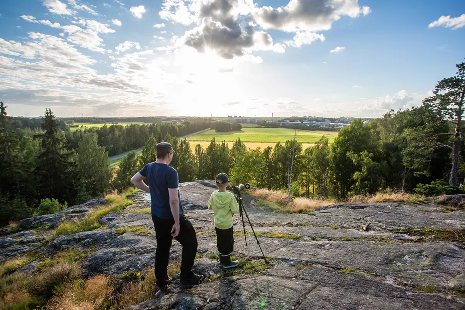 Mies ja lapset kiikaroivat kalliolla