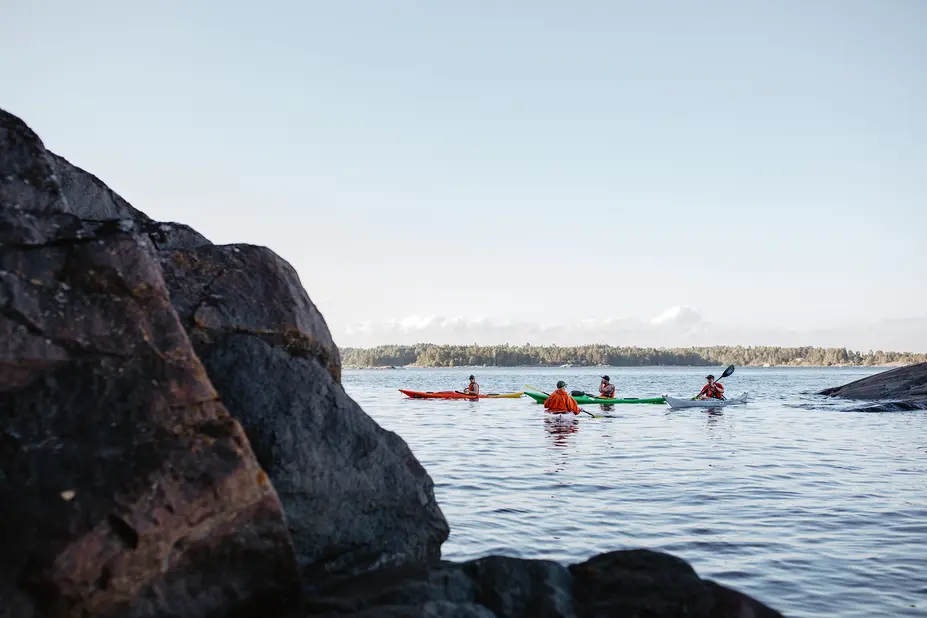 People canoeing on the sea among rocks.