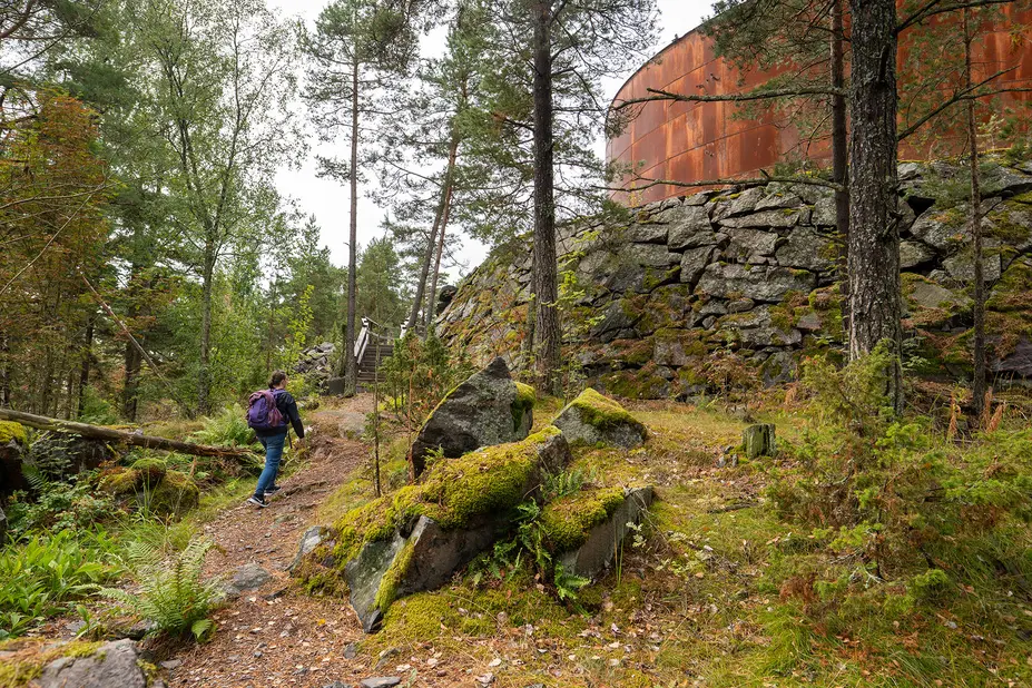 Retkeilijä kulkee polulla kohti vanhaa öljysäiliötä