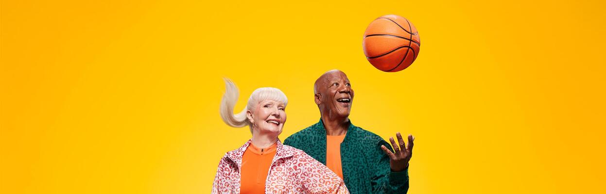 Två äldre personer, varav den ena kastar en basketboll i luften.