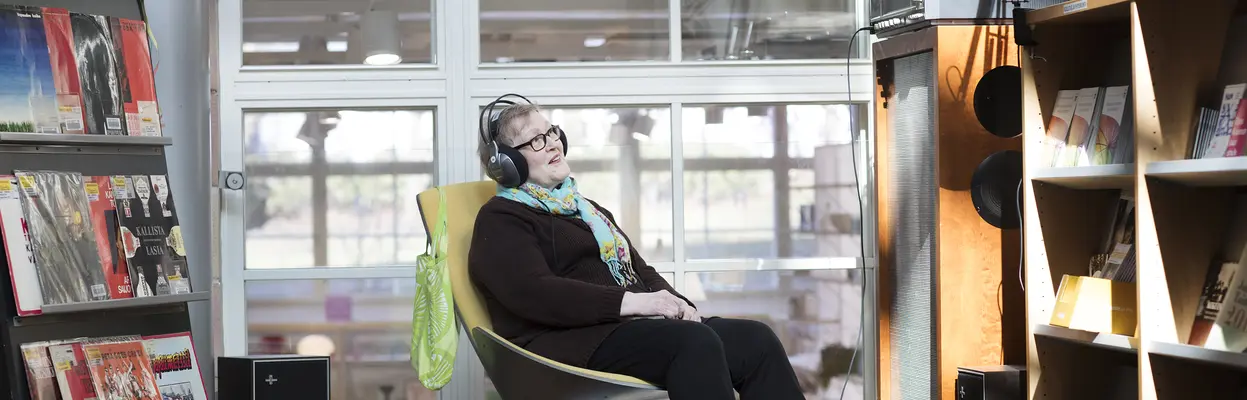 The person is listening to music in the library.