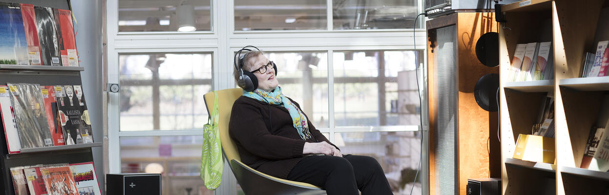 The person is listening to music in the library.