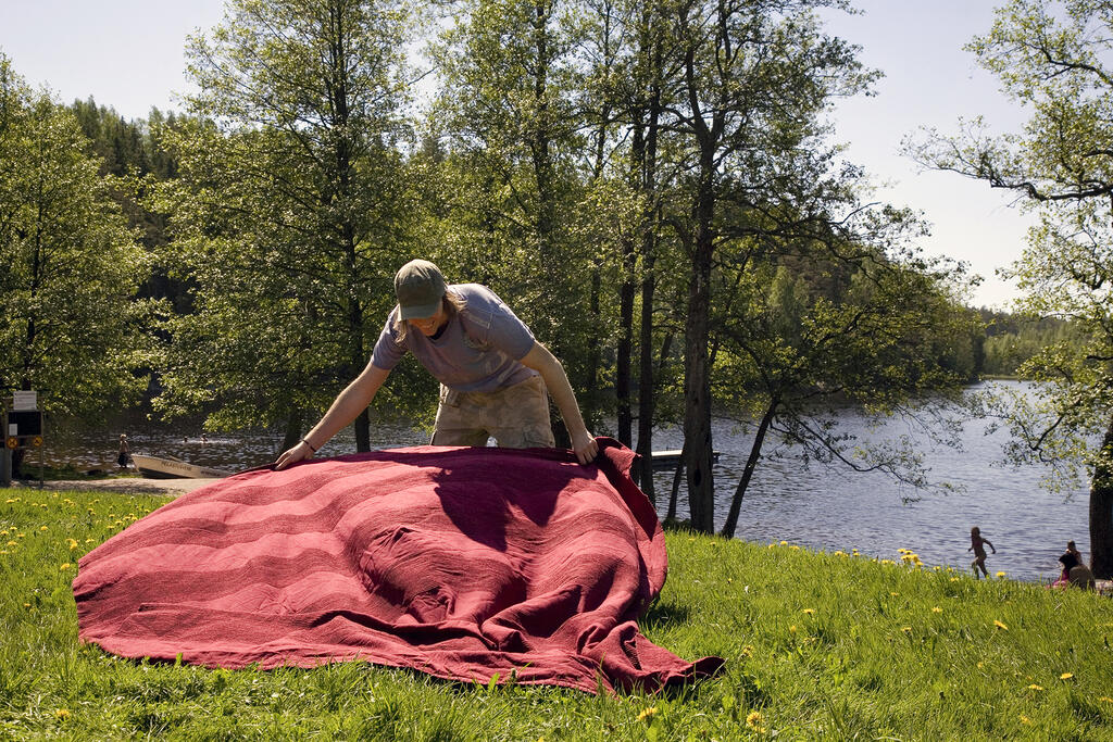 A person spreading a blanket on a lawn.