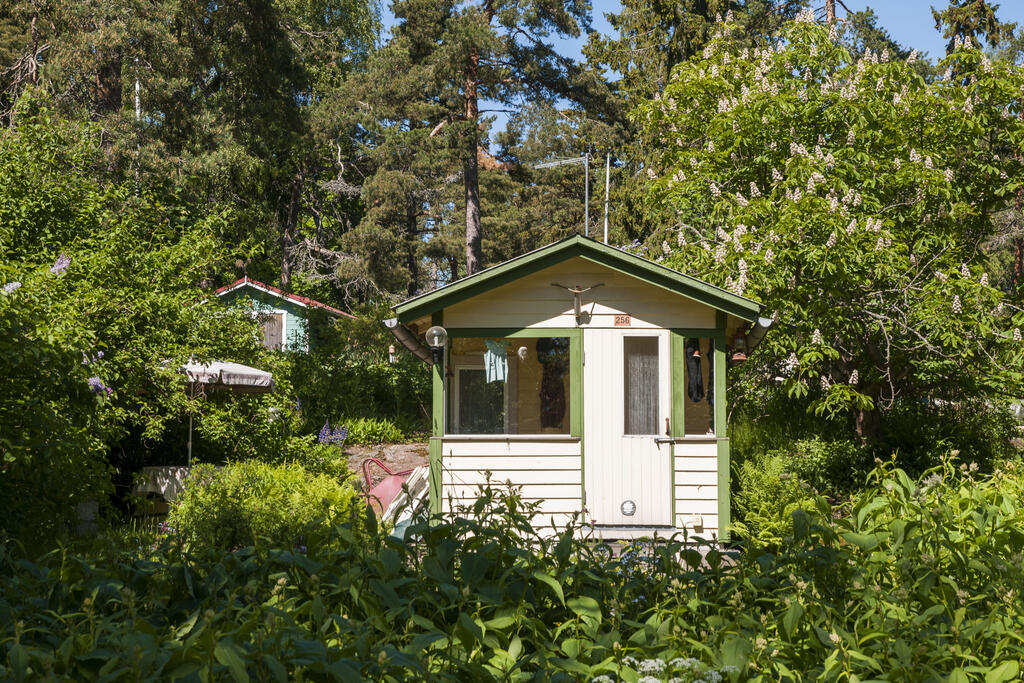 A cream-coloured summer lodge in a lush landscape.