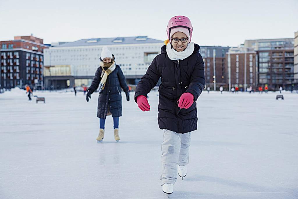A woman and a girl are skating on Jätkäsaari artificial ice rink.