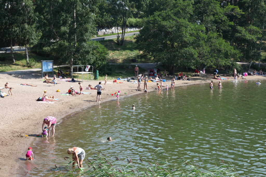 Ihmiset viettävät kesäistä päivää uimarannalla.