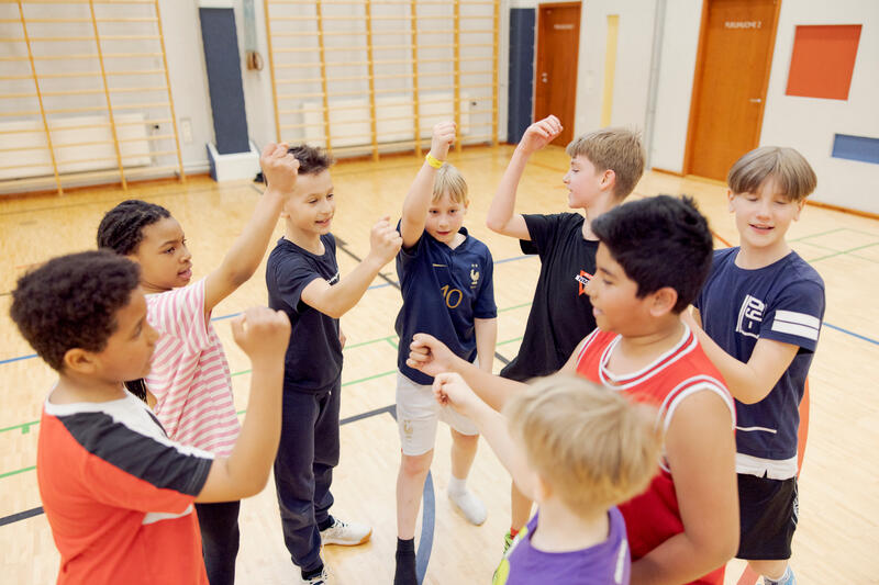 Lapsia ja nuoria koripalloharrastuksessa loppuhuutoa tekemässä.