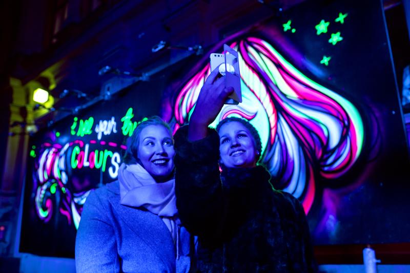 Lux Helsinki 2018. En vinterkväll. Kvinnor tar en selfie vid fluorescerande konst.
