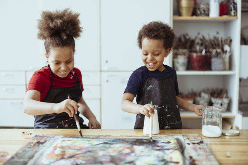 Kuvituskuva, jossa kaksi lasta maalaa siveltimillä.