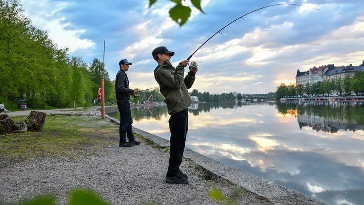 Kaksi nuorta kalastaa Kaisaniemenrannassa.