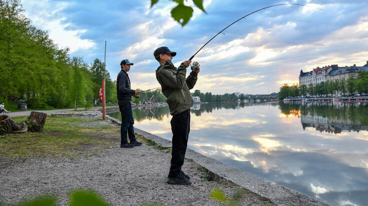 Kaksi nuorta kalastaa Kaisaniemenrannassa.