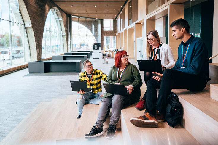 Ryhmä työntekijöitä istumassa kaupunkiympäristötalon aulassa.