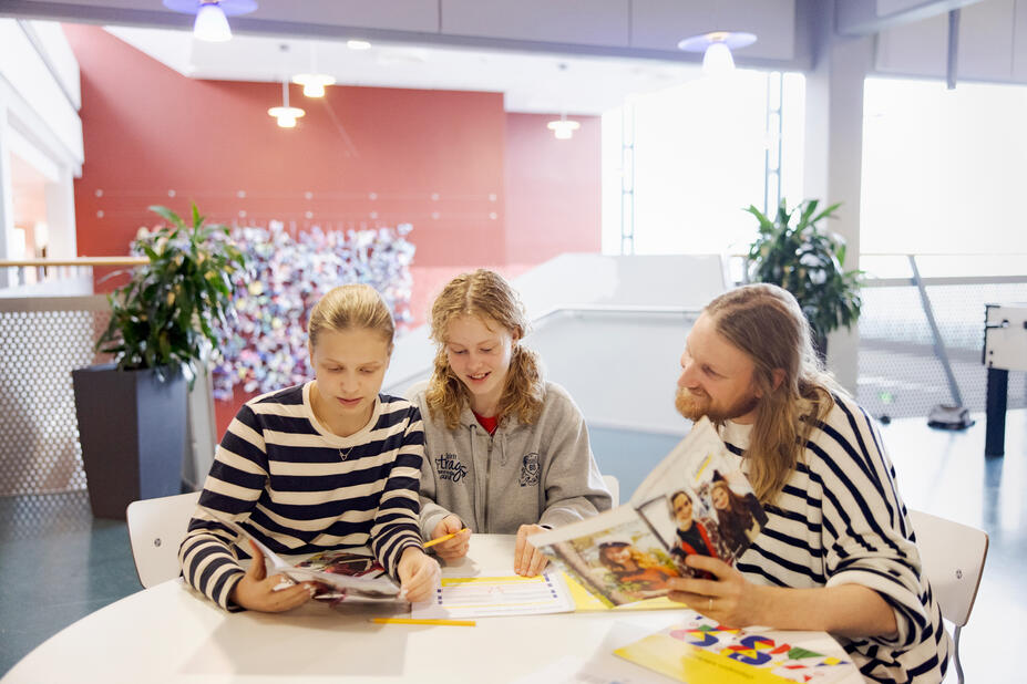 En studiehandlare med två unga vid ett bord.