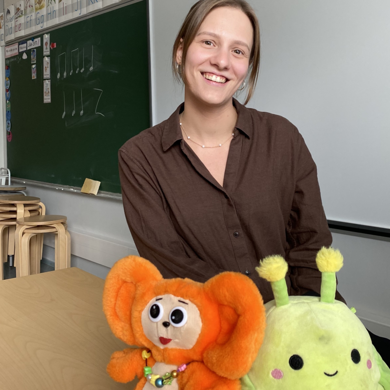 Kuvassa opettaja Jonna Jokilahti luokkahuoneessaan. Kuvassa etualalla luokan pehmolelut Riiviö ja Mini.