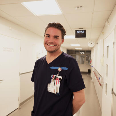 Antti Laitinen seisoo Laakson sairaalan osaston käytävällä ja hymyilee kameralle.