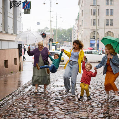 Monimuotoinen perhe kadulla sateessa