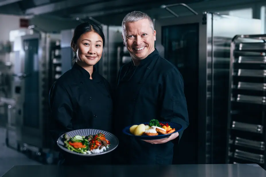 Two workers holding plates of food.