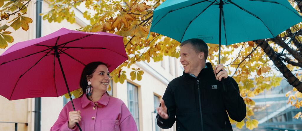 Nainen ja mies sateenvarjojen kanssa syksyisessä Helsingissä.