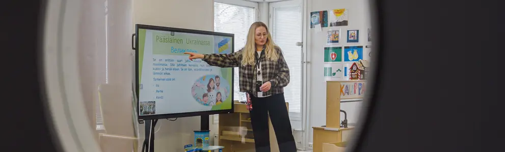 Varhaiskasvatuksen opettaja opettaa lapsia ison näytön avulla.