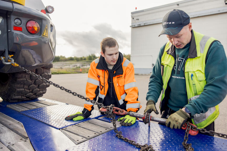 Kaksi kuljetusalan opiskelijaa harjoittelee kiinnitystä.