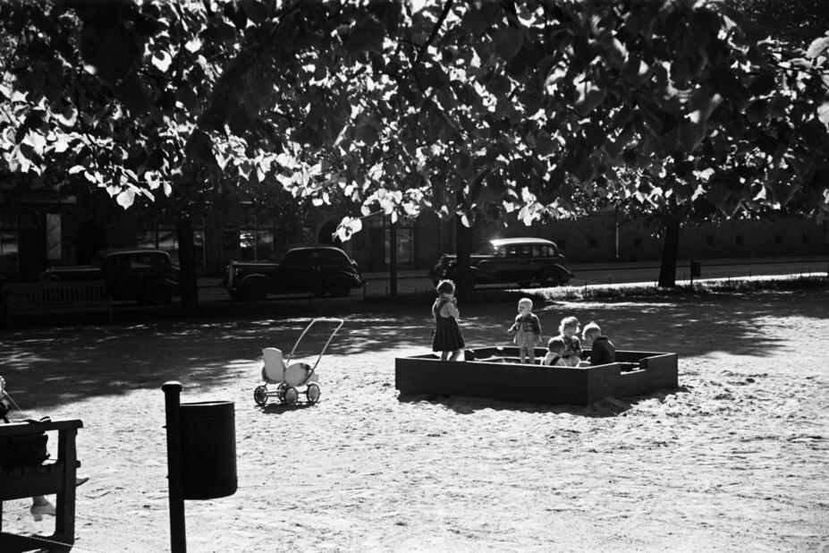 Mustavalkoinen kuva lapsista hiekkalaatikossa 1950-luvulla.