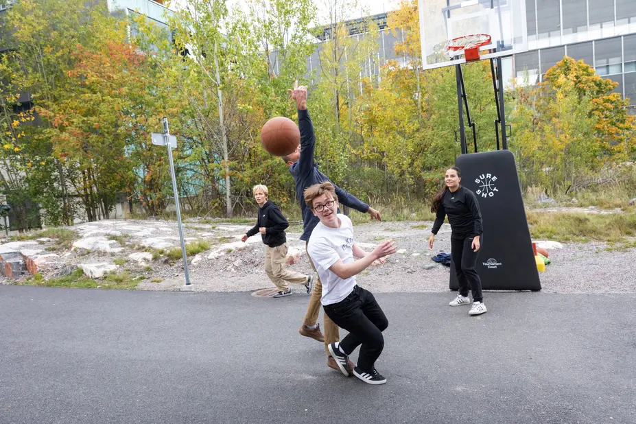 Opiskelijat pelaavat pihalla koripalloa