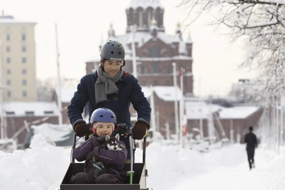 A man and a child biking in Helsinki in winter