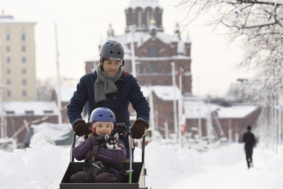 A man and a child biking in Helsinki in winter