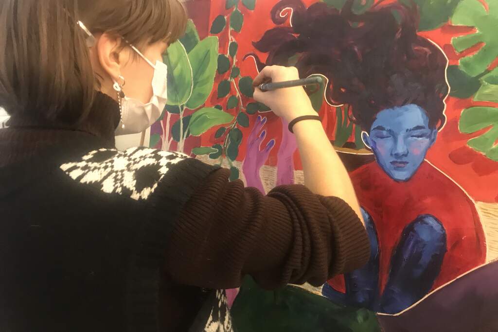 Opiskelija maalaa puna-sinistä öljyvärimaalausta