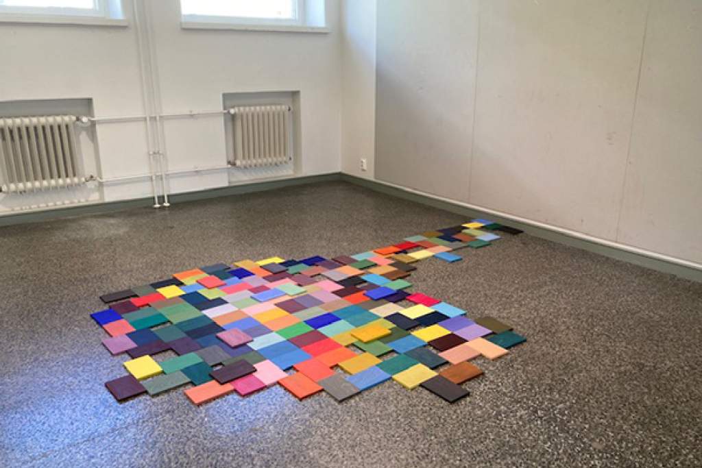 Värillisiä puupaloja järjestettynä lattialle.