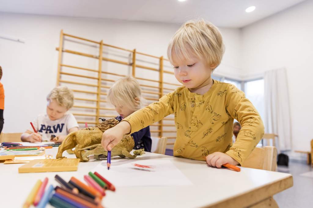 Lapsia päiväkodissa piirtämässä pöydän ääressä