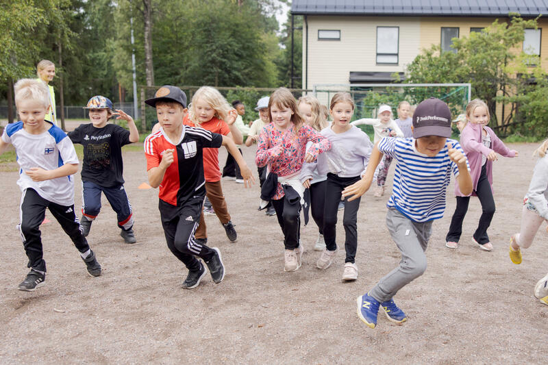 Lapsia juoksee koulun pihalla leikkimässä.