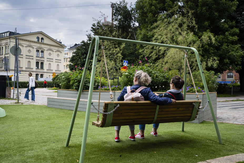 Ihmisiä keinussa kesäisessä Helsingissä