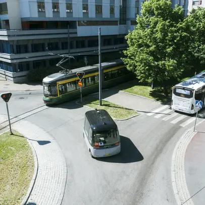Liikenneympyrässä raitiovaunu, bussi, kutsuauto ja pyöräilijä.