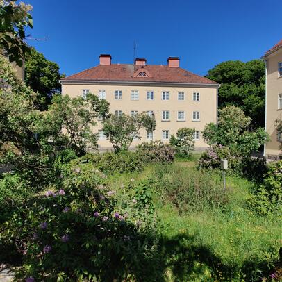 Vehreä sisäpihakortteli. Korttelissa kolme kolmekerroksista vaaleaa kerrostaloa.