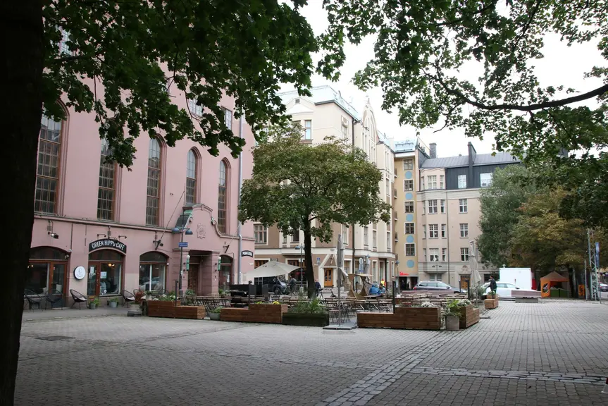 Toria ympäröi vanhat talot. Torilla on terassi ja siellä kasvaa muutama puu.
