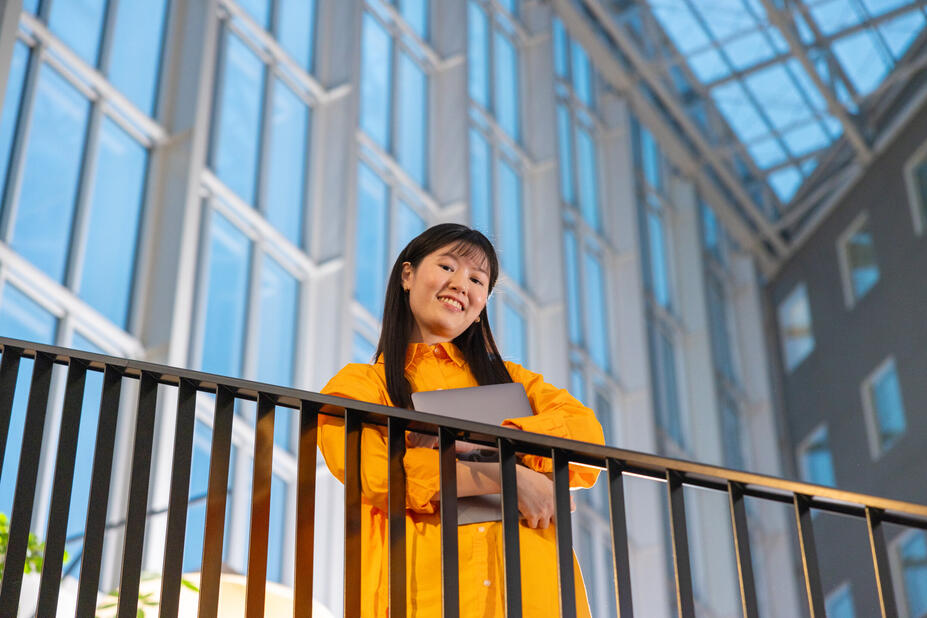 En person som står på en vind, tittar ner, med en bärbar dator i knät.