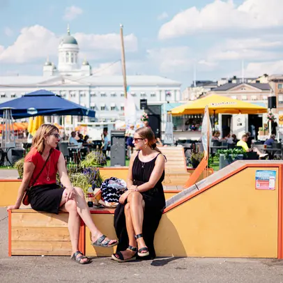 Två kvinnor som sitter på torget.
