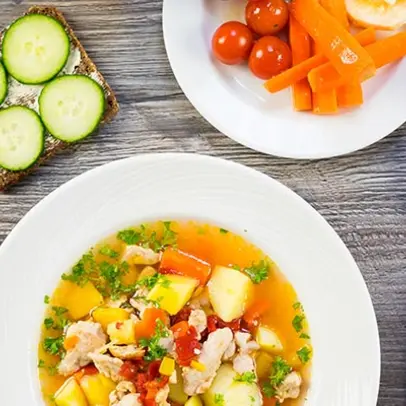 Kycklingsoppa med sallad, bröd och måltidsdryck.