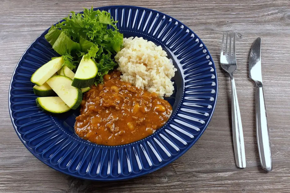 Lautasella Chili con Carnea salaatin ja riisin kera.