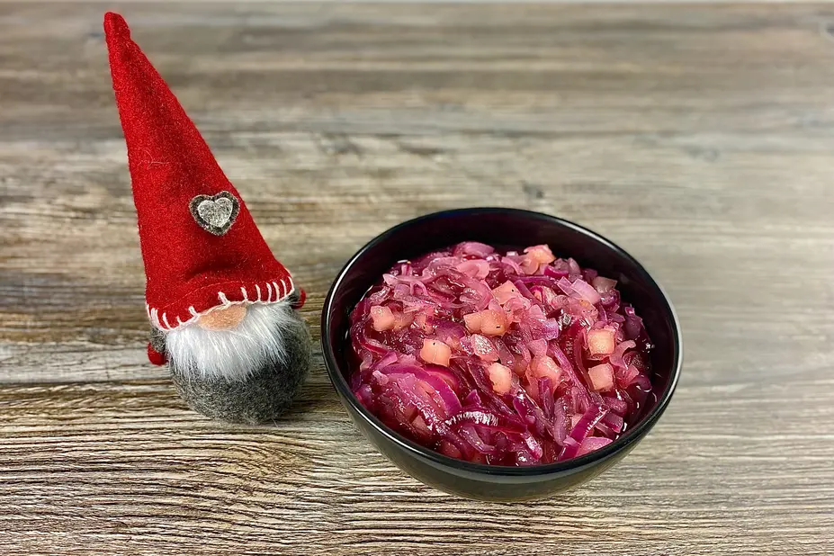 Tonttu ja kulhollinen punasipuli-omenahilloketta pöydällä.