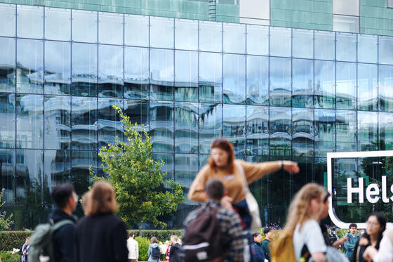 Ihmisiä ulkona, taustalla talo.