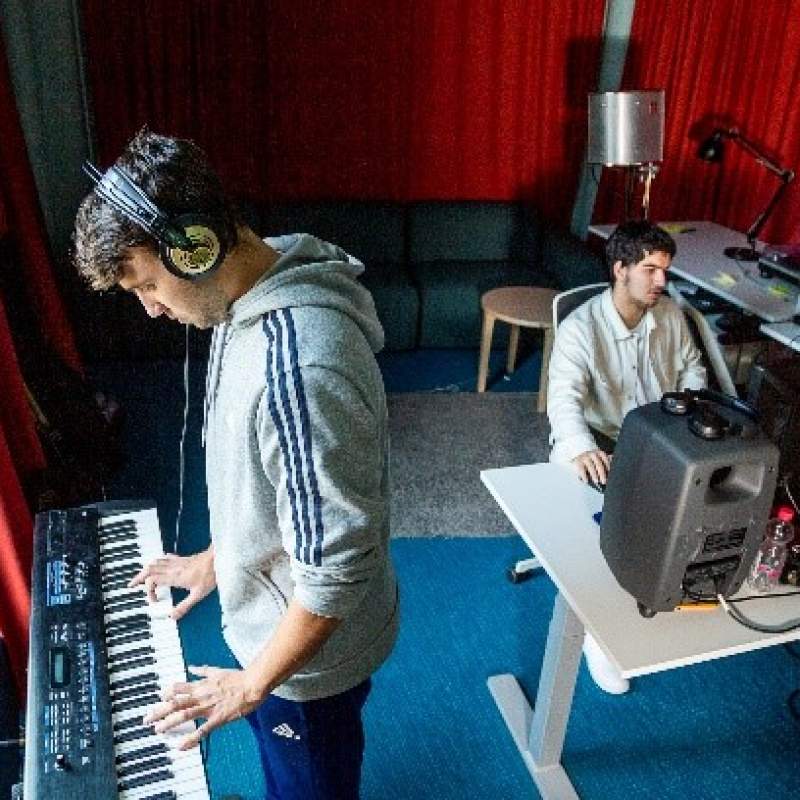 Two young boys work in a recording studio.