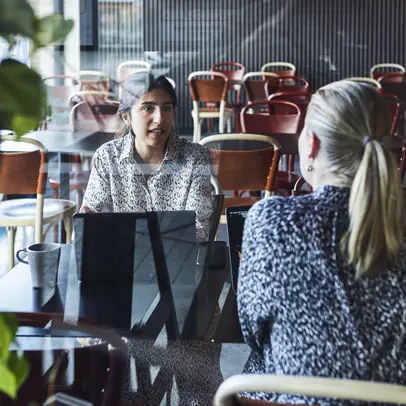Two women talk to each other at the table.