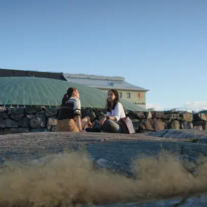 Two people sitting in the summer evening sun outside the Temppeliaukio Church.