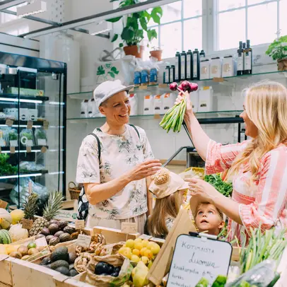 Two happy people buying vegetables in the Hakaniemi Market Hall.