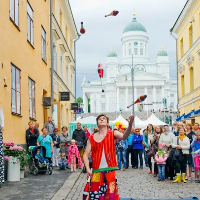An audience watching a juggler's tricks in the Helsinki market quarters.