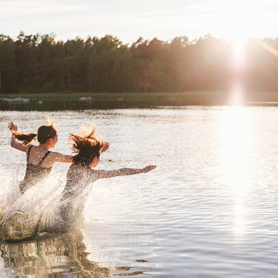 Kaksi henkilöä juoksee uimaan.